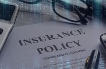 Insurance Policy on table with technology around to depict cyber insurance