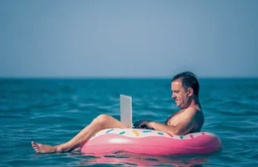 mid age man working on laptop while floating in the sea summer vacation
