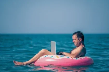 mid age man working on laptop while floating in the sea summer vacation