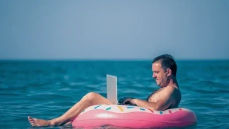 mid age man working on laptop while floating in the sea summer vacation